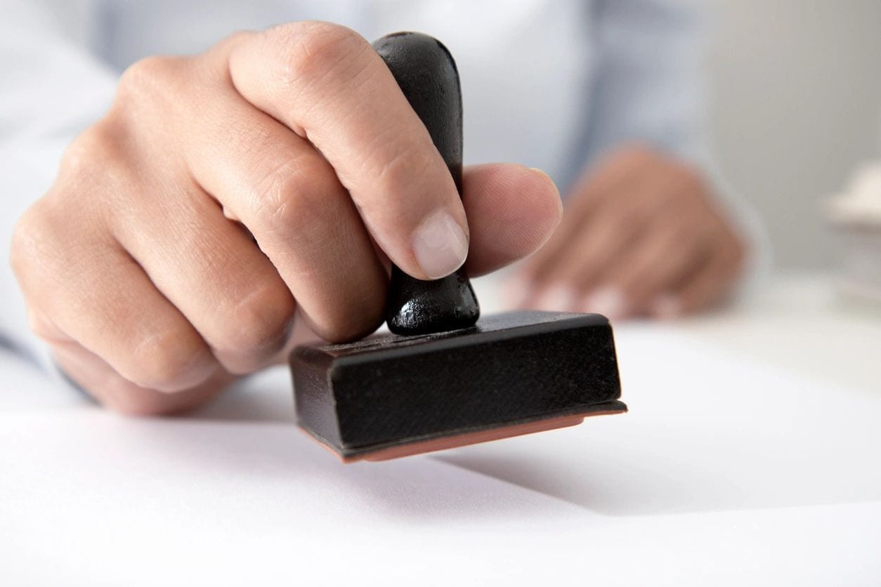A person is using a rubber stamp to seal the paper.